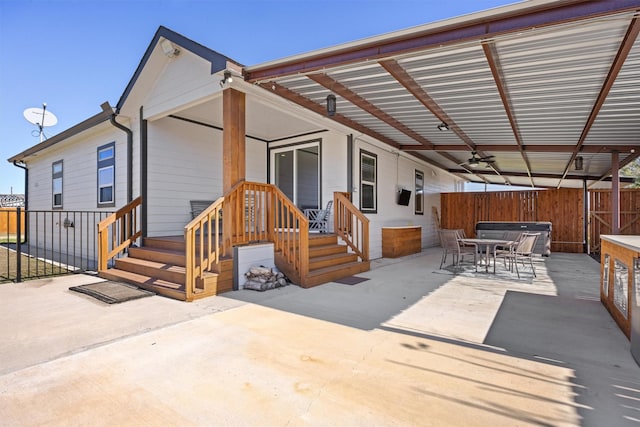 rear view of house featuring ceiling fan, a patio, and a hot tub