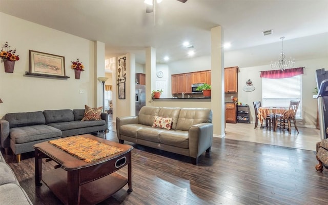 living room featuring ceiling fan with notable chandelier and dark hardwood / wood-style flooring