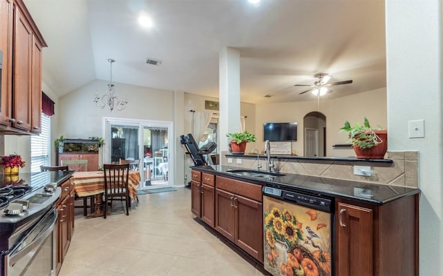 kitchen featuring vaulted ceiling, pendant lighting, ceiling fan with notable chandelier, sink, and stainless steel appliances