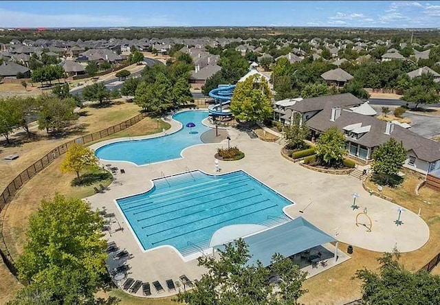 community pool featuring a residential view, fence, a water slide, and a patio