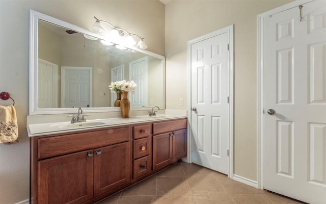 full bath featuring baseboards, tile patterned flooring, double vanity, and a sink