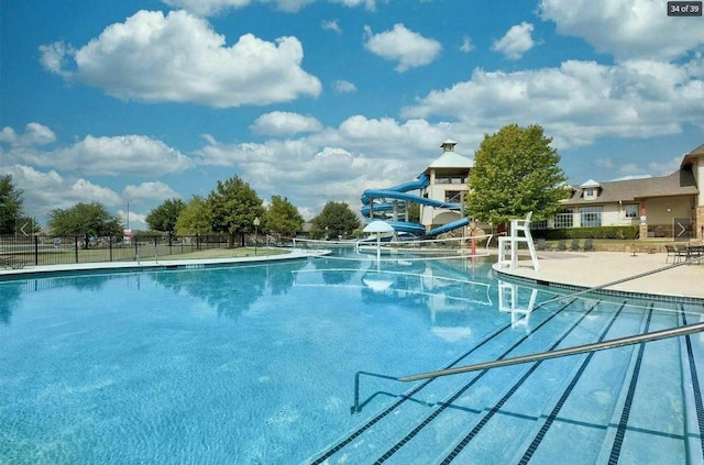 community pool with fence and a water slide