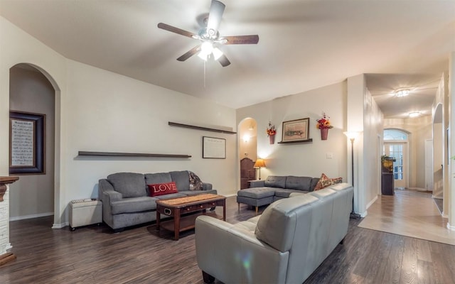living room with dark wood-style flooring, arched walkways, a ceiling fan, and baseboards