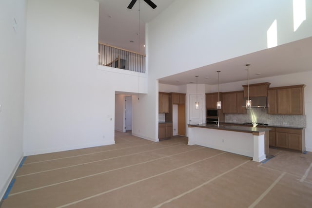 kitchen with a high ceiling, pendant lighting, backsplash, ceiling fan, and stainless steel gas stovetop