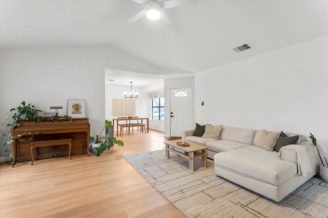 living room with ceiling fan with notable chandelier, lofted ceiling, and light wood-type flooring