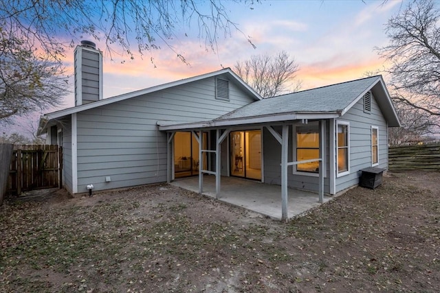 back house at dusk featuring a patio area