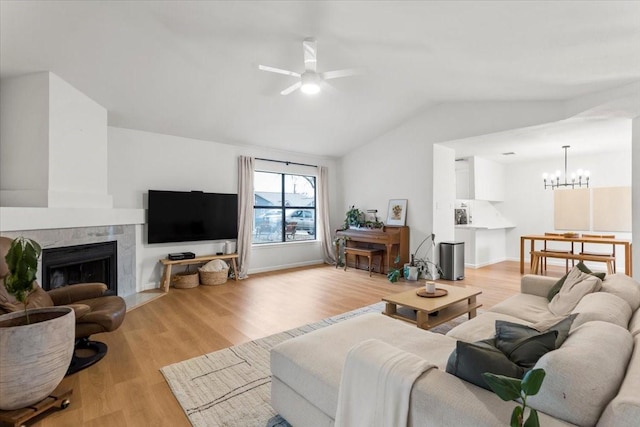 living room with a fireplace, ceiling fan with notable chandelier, light hardwood / wood-style flooring, and lofted ceiling