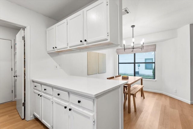 kitchen featuring decorative light fixtures, a chandelier, white cabinetry, and light hardwood / wood-style flooring