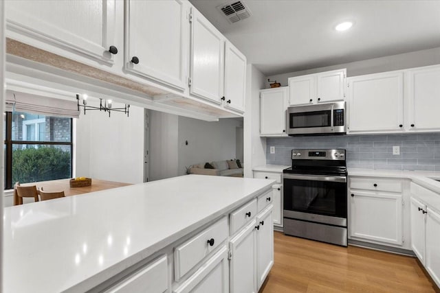 kitchen featuring a notable chandelier, decorative backsplash, white cabinets, light hardwood / wood-style flooring, and stainless steel appliances