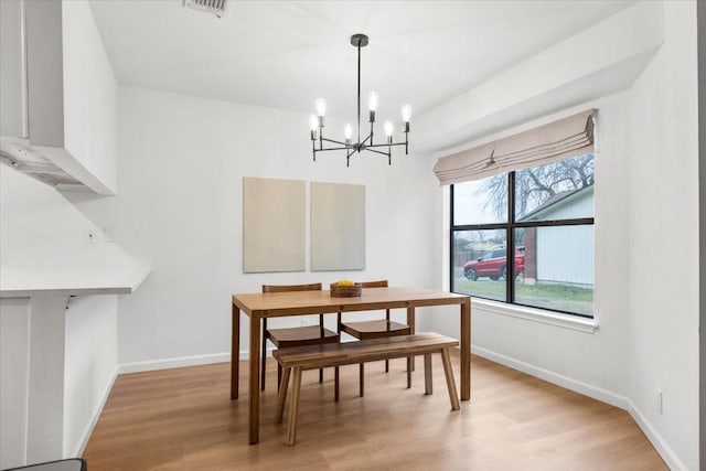 dining area featuring light wood-type flooring and a notable chandelier