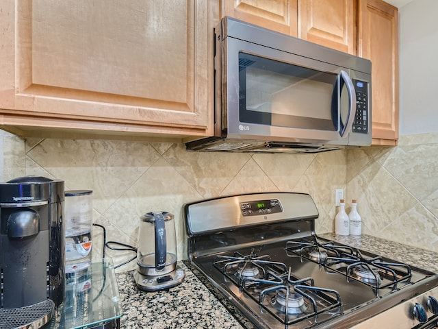 kitchen with stainless steel appliances, light brown cabinets, stone countertops, and backsplash