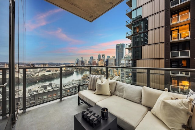 balcony at dusk with an outdoor living space and a water view