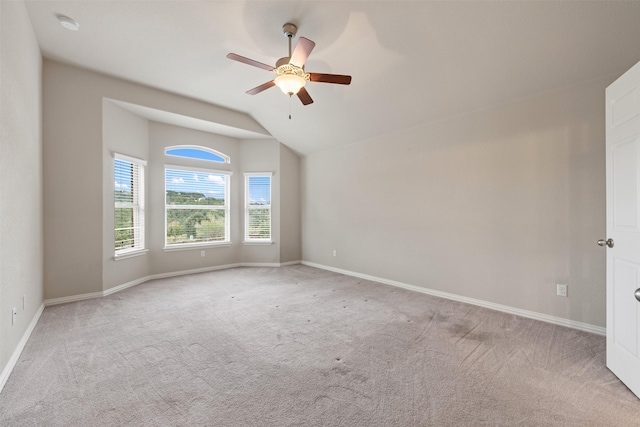 empty room with light colored carpet, vaulted ceiling, and ceiling fan