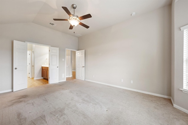 unfurnished bedroom with ensuite bath, multiple windows, vaulted ceiling, ceiling fan, and light colored carpet