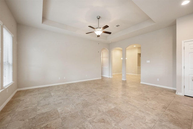 spare room featuring ceiling fan and a raised ceiling