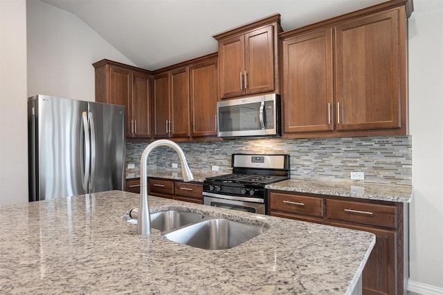 kitchen with appliances with stainless steel finishes, sink, tasteful backsplash, light stone counters, and lofted ceiling