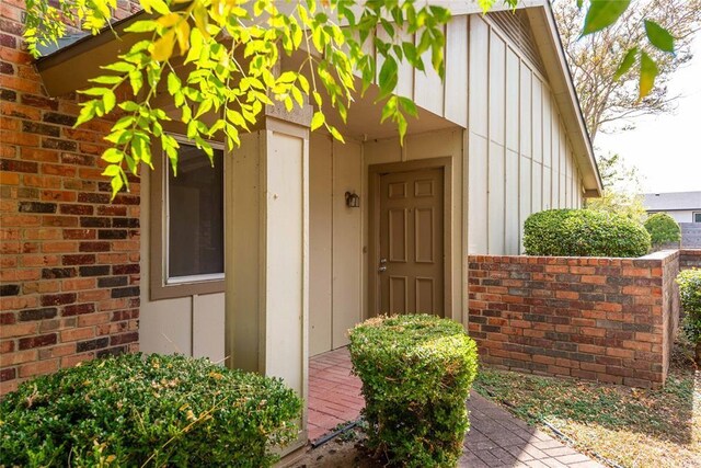 view of exterior entry featuring brick siding and board and batten siding