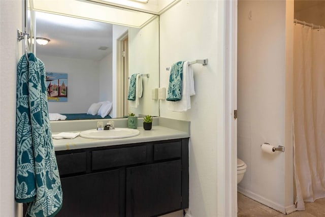 bathroom featuring tile patterned flooring, toilet, vanity, and baseboards