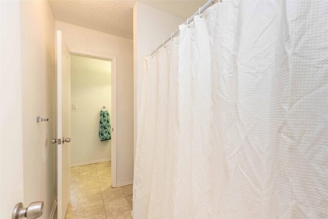 full bathroom with tile patterned floors, baseboards, and a textured ceiling