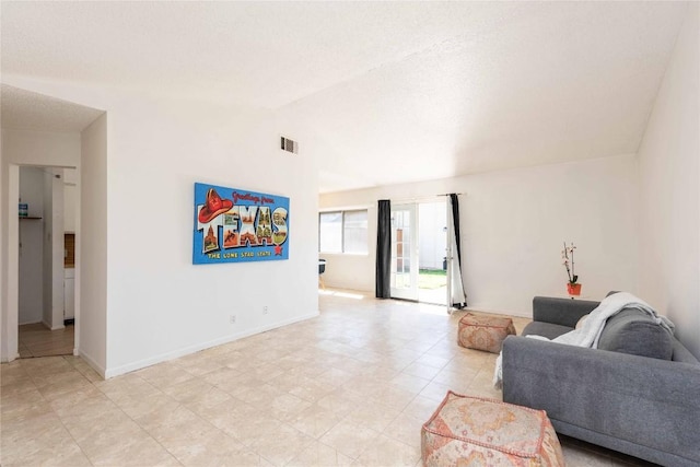 living room with visible vents, lofted ceiling, and baseboards