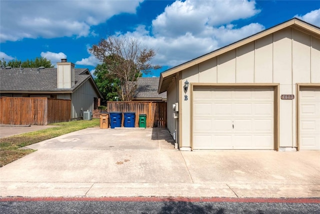 view of front facade featuring concrete driveway, fence, central AC unit, and a garage