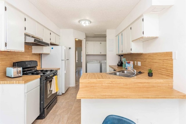 kitchen with black gas range oven, a peninsula, separate washer and dryer, a sink, and under cabinet range hood