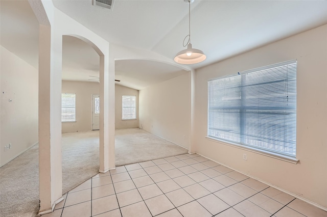 tiled empty room featuring vaulted ceiling