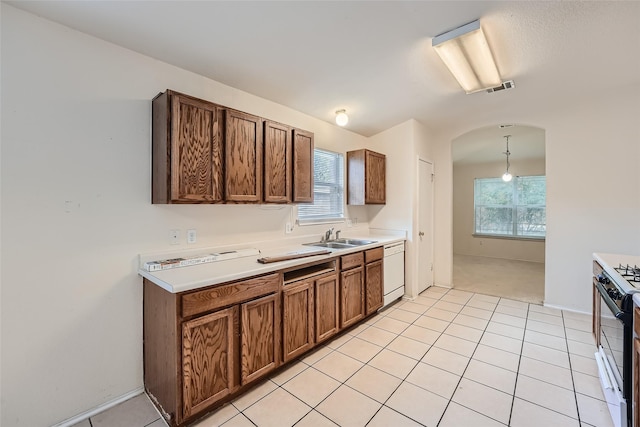 kitchen with white dishwasher, light tile patterned floors, gas range, sink, and pendant lighting