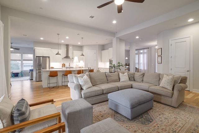 living room with sink, ceiling fan, and light hardwood / wood-style floors