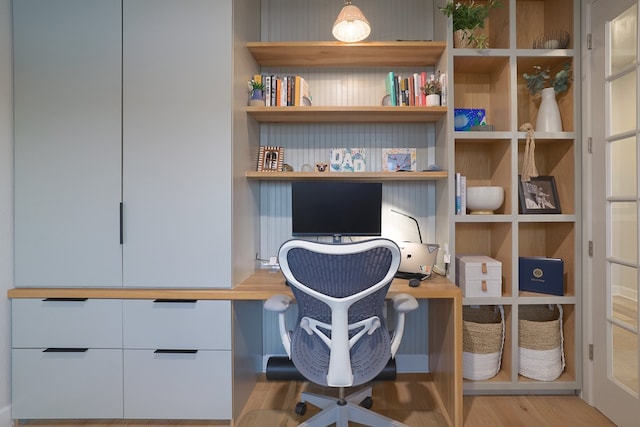 office space with built in desk and light hardwood / wood-style floors