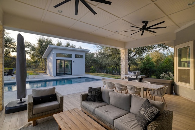 view of swimming pool with ceiling fan, a grill, an outbuilding, and an outdoor living space