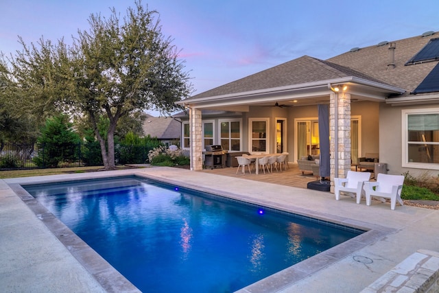 pool at dusk featuring ceiling fan, a patio area, an outdoor living space, and a grill