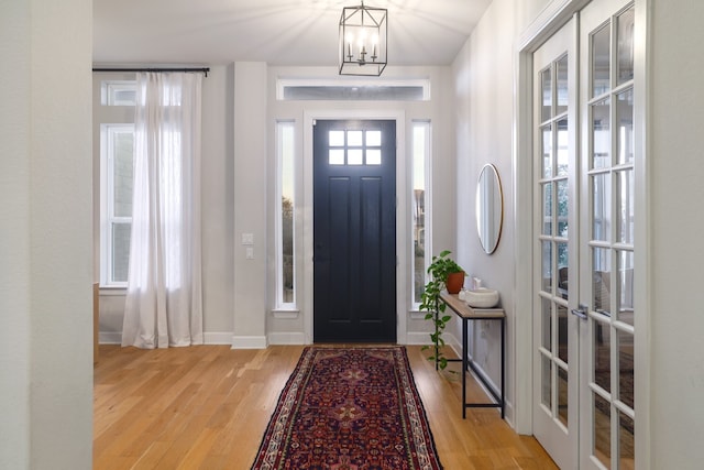 entryway featuring light hardwood / wood-style floors, a chandelier, and french doors