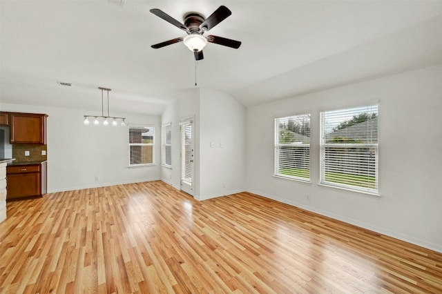 unfurnished living room with visible vents, baseboards, vaulted ceiling, light wood-style flooring, and a ceiling fan