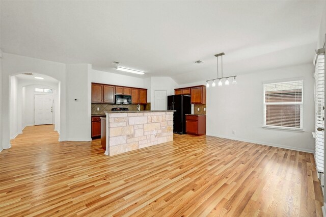 kitchen featuring light hardwood / wood-style flooring, hanging light fixtures, tasteful backsplash, a center island, and black appliances