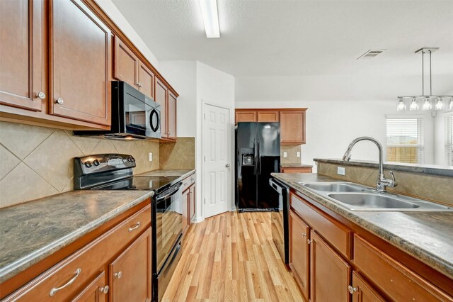 kitchen featuring black appliances, light hardwood / wood-style floors, sink, backsplash, and hanging light fixtures