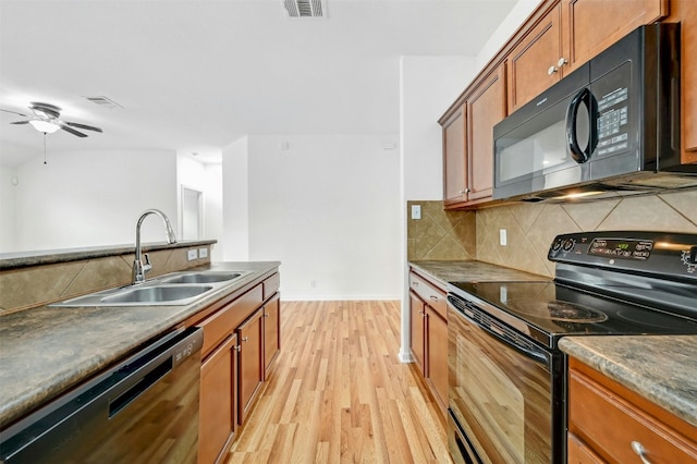 kitchen featuring visible vents, brown cabinets, black appliances, and a sink