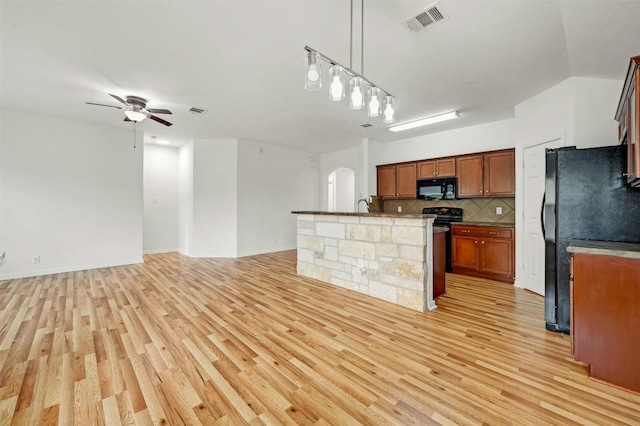 kitchen featuring visible vents, arched walkways, decorative backsplash, black appliances, and light wood-type flooring