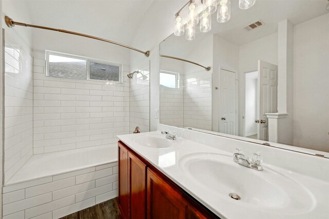 bathroom with wood-type flooring, vanity, a wealth of natural light, and tiled shower / bath