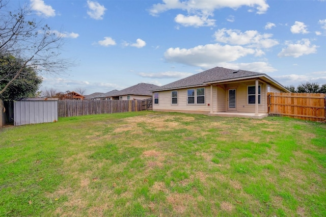 back of property with a storage unit, an outbuilding, a patio, a fenced backyard, and a yard