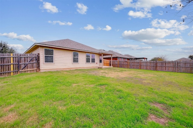 rear view of house featuring a yard and a fenced backyard