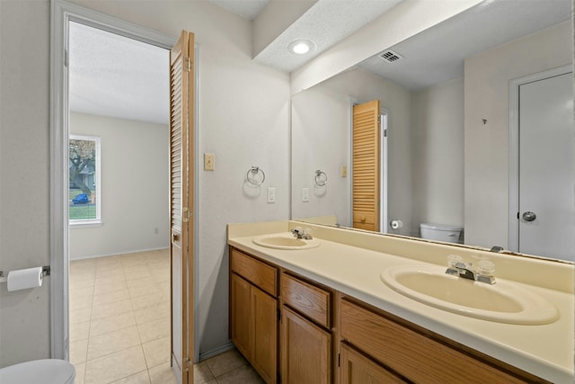 bathroom featuring vanity, toilet, tile patterned floors, and a textured ceiling