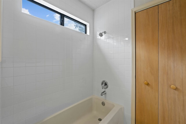 bathroom featuring a textured ceiling and tiled shower / bath combo