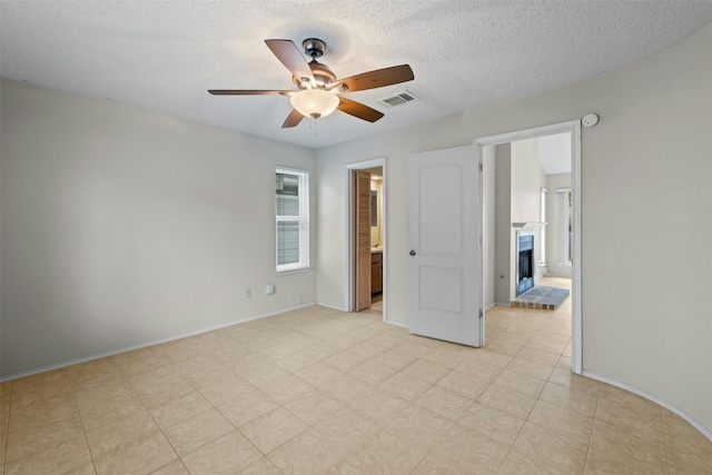 unfurnished bedroom featuring ceiling fan, ensuite bathroom, and a textured ceiling