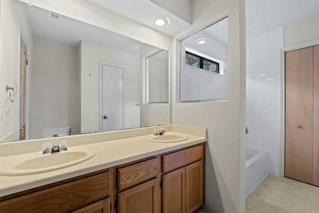 full bathroom with toilet, a textured ceiling, tile patterned flooring, vanity, and tub / shower combination