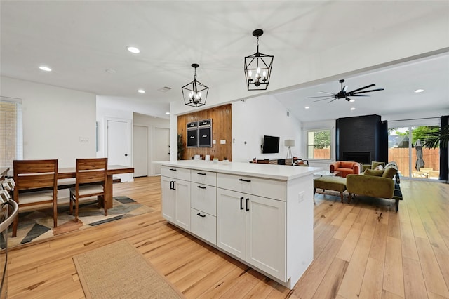 kitchen with decorative light fixtures, light hardwood / wood-style floors, white cabinets, and a kitchen island