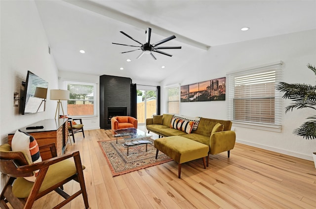 living room with lofted ceiling with beams, light hardwood / wood-style flooring, ceiling fan, and a large fireplace