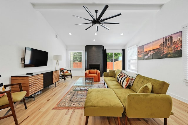 living room featuring a large fireplace, light hardwood / wood-style flooring, and vaulted ceiling with beams