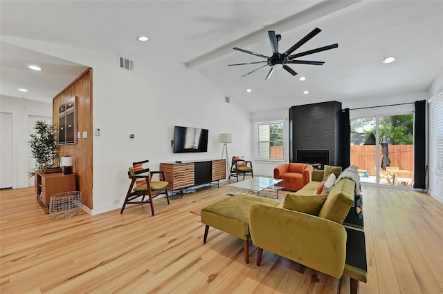 living room featuring a large fireplace, light wood-type flooring, ceiling fan, and lofted ceiling with beams