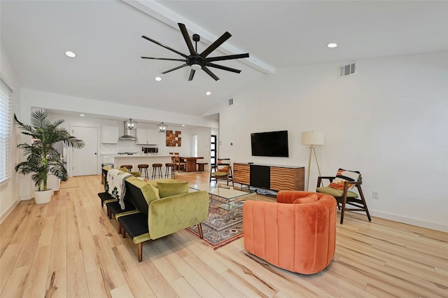 living room with vaulted ceiling with beams, light hardwood / wood-style floors, and plenty of natural light